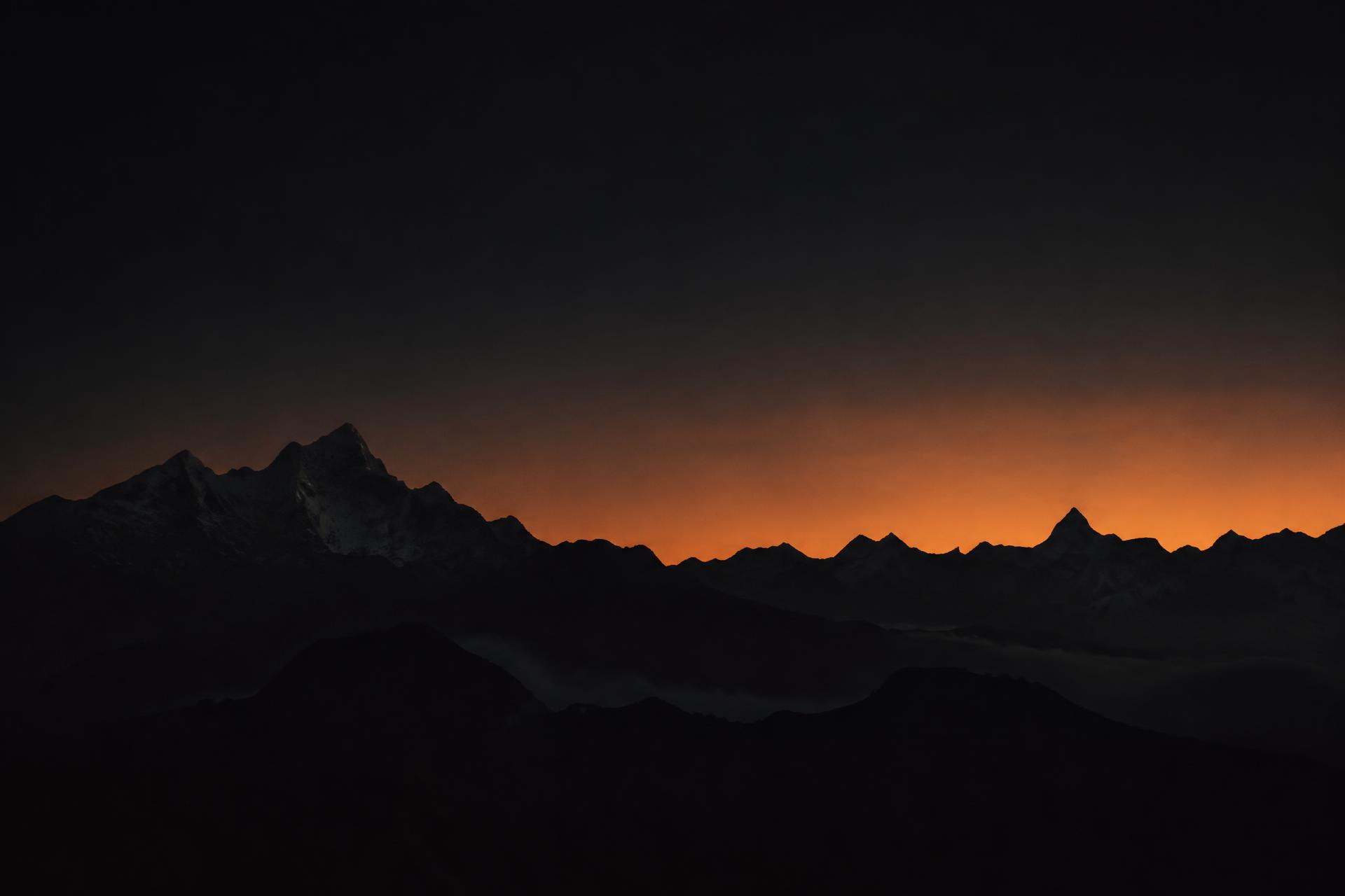 Mountain ridgeline silhouetted against an ember dawn sky